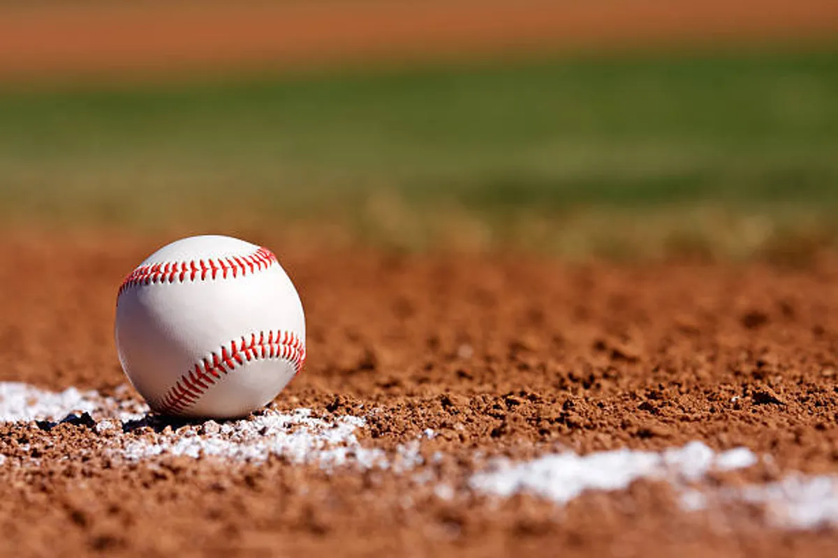 A close-up view of a baseball on the dirt infield with a crisp white chalk line, capturing the essence of game day and the excitement of being near sports venues.