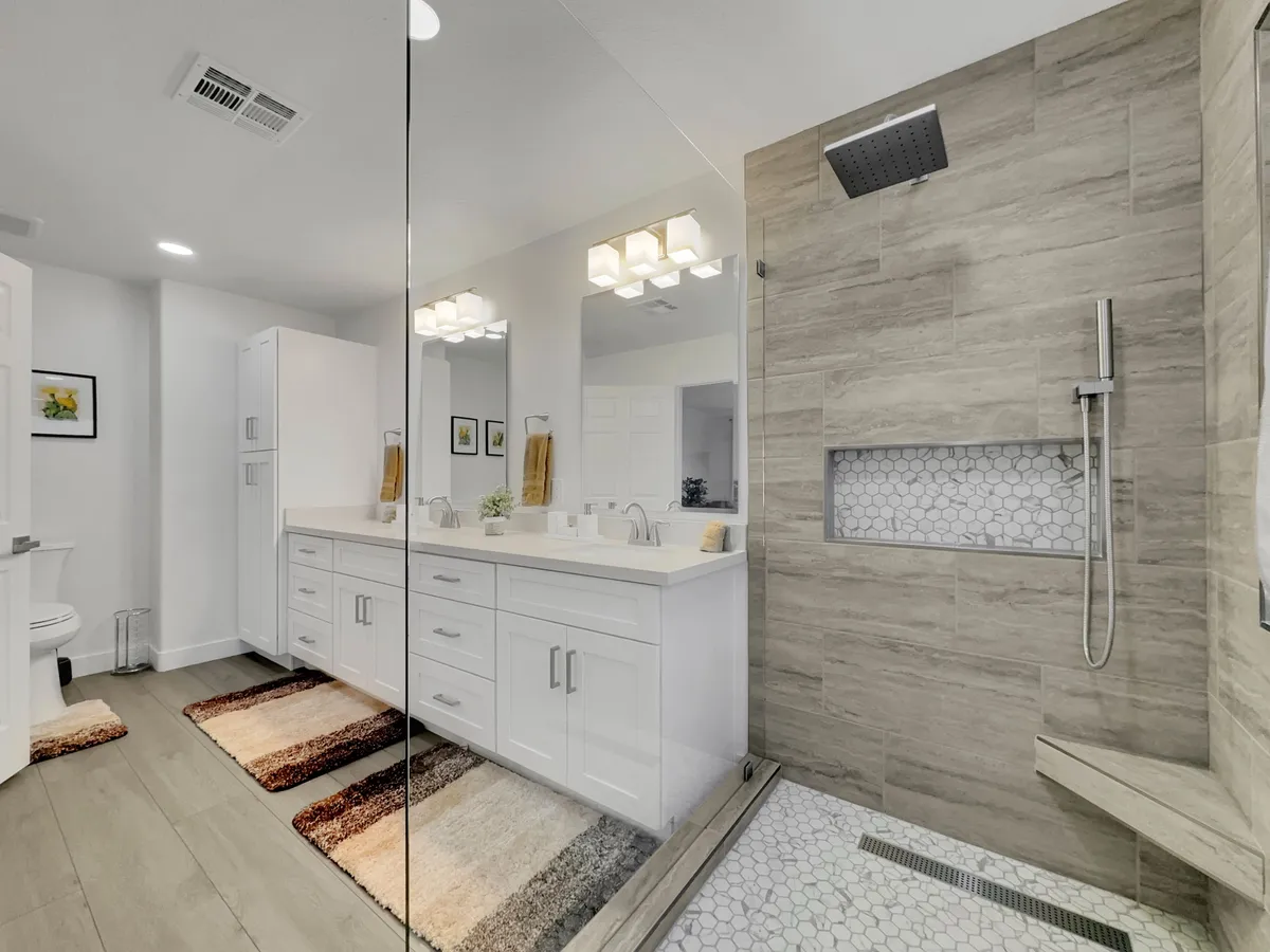 A spa-like bathroom featuring a double vanity, walk-in shower with glass doors, mirrored cabinets, and soft, inviting lighting. The room exudes calm and relaxation, ideal for self-care routines and refreshing mornings.