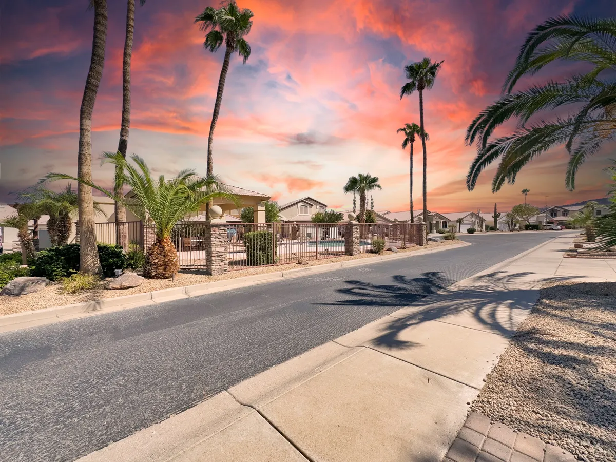 A scenic exterior shot featuring palm trees, a shimmering swimming pool, residential buildings, and a colorful evening sky—evoking the atmosphere of nearby entertainment and leisure.